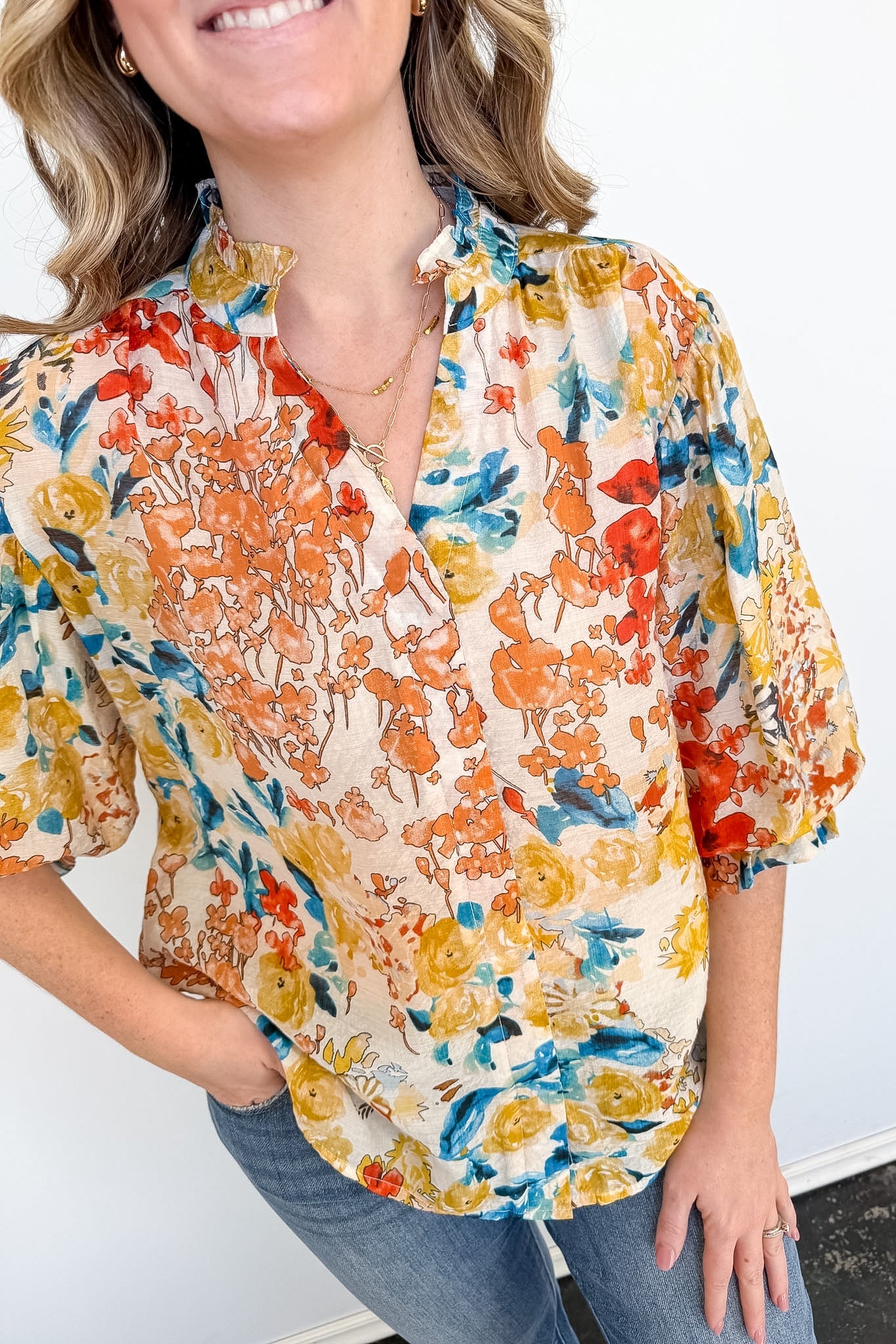 Woman wearing a colorful floral blouse against a white background