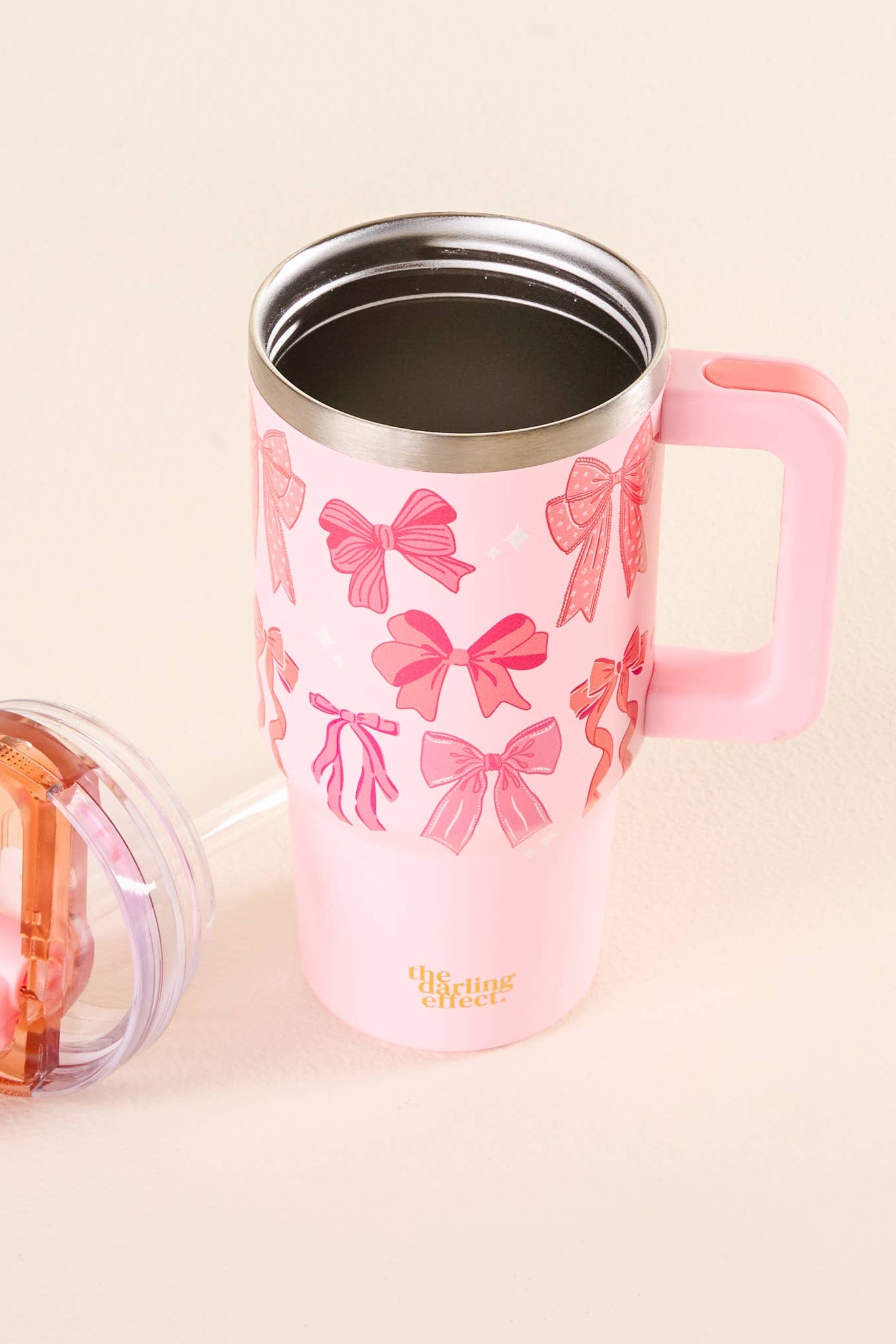 Pink tumbler with bow pattern and pink handle on a beige background