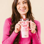 Woman holding a pink tumbler with a floral design against a beige background