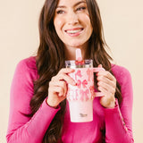 Woman holding a pink tumbler with a floral design against a beige background