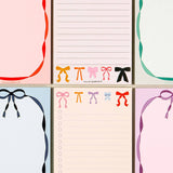 Set of six notepads with colorful bow designs on a light beige background