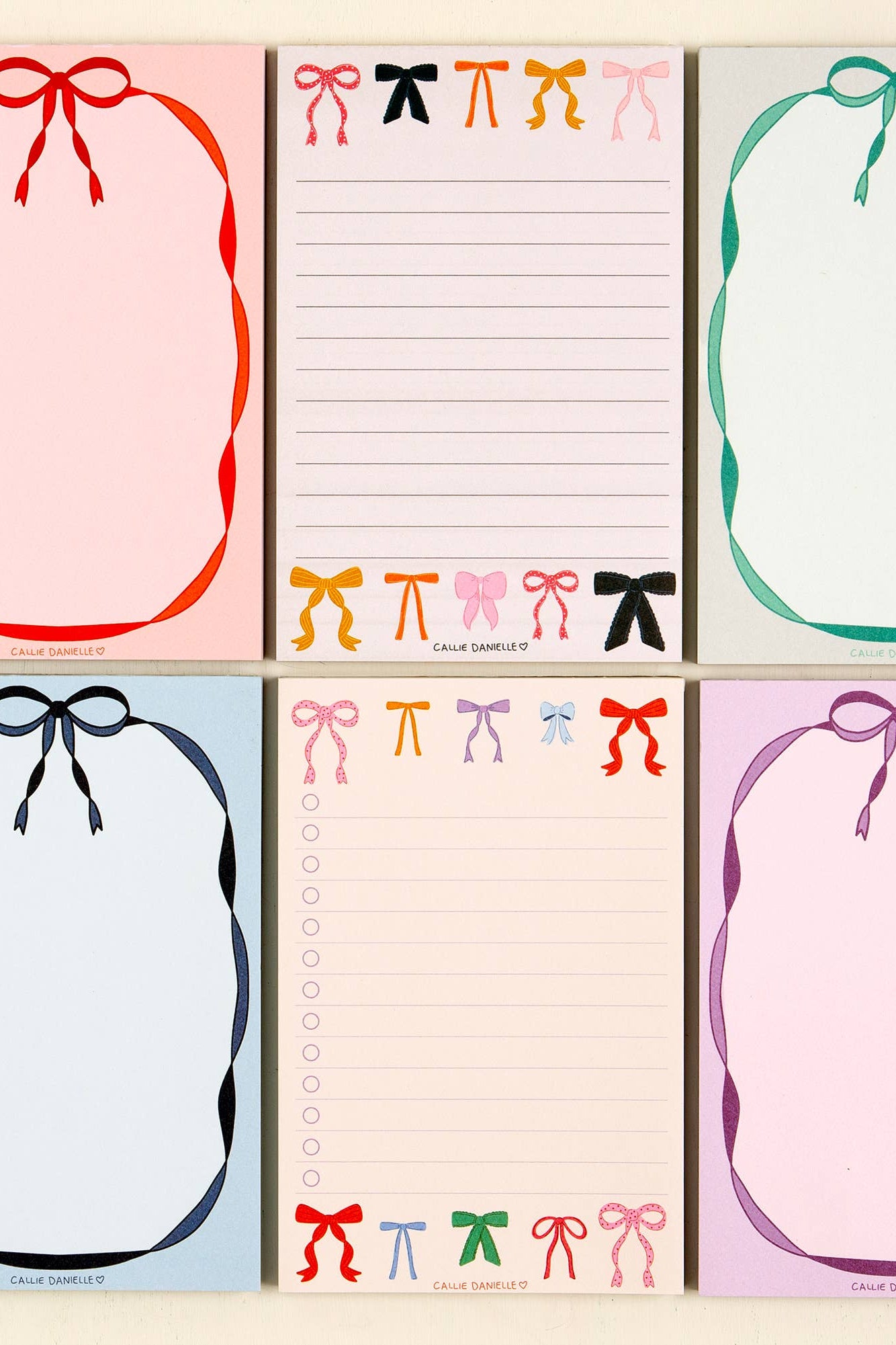 Set of six notepads with colorful bow designs on a light beige background