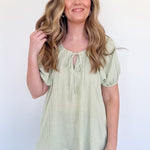 Woman wearing a light green striped blouse and blue jeans against a white background