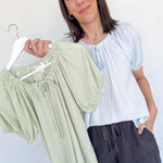 Woman holding a hanger with green striped pants against a white background