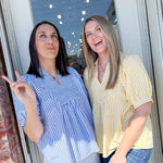 Two women standing by a door, one pointing outside.