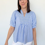Woman wearing a blue and white striped blouse against a white background