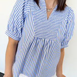 Woman wearing a blue and white striped shirt against a white background