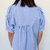Person wearing a blue and white striped shirt with a plain background