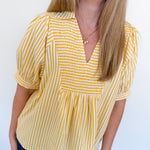 Woman wearing a yellow and white striped blouse against a white background