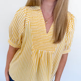 Woman wearing a yellow and white striped blouse against a white background