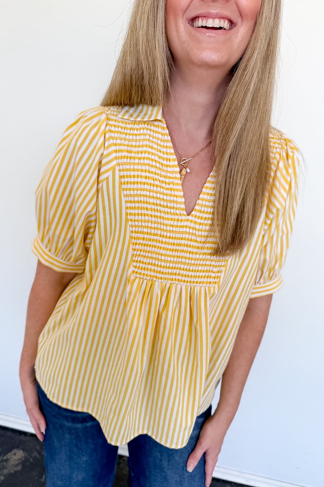 Woman wearing a yellow and white striped blouse against a white background