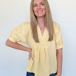 Woman wearing a yellow striped blouse and blue jeans against a white background