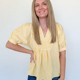 Woman wearing a yellow striped blouse and blue jeans against a white background