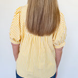 Person wearing a yellow and white striped shirt with blue jeans against a white background