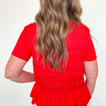 Person wearing a red blouse with a plain background