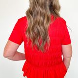 Person wearing a red blouse with a plain background