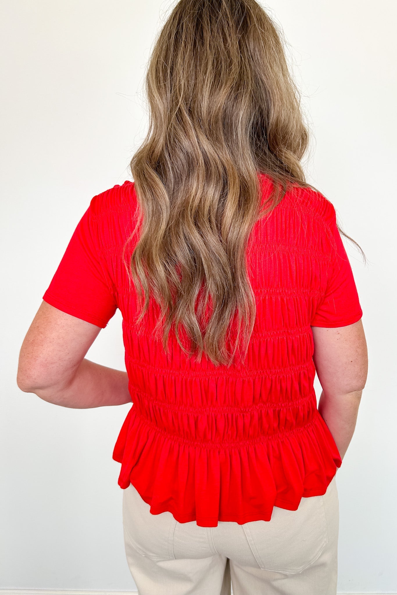 Person wearing a red blouse with a plain background
