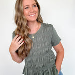 Woman wearing a green ruffled top and blue jeans against a white background