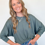 Woman wearing a green sweater and blue jeans against a white background