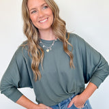 Woman wearing a green sweater and blue jeans against a white background