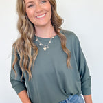 Woman wearing a green sweater and blue jeans against a white background