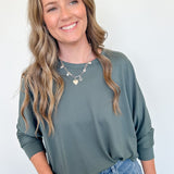Woman wearing a green sweater and blue jeans against a white background