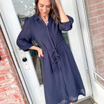 Woman wearing a navy blue dress standing in front of a door.