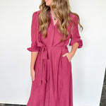 Woman wearing a pink dress against a white wall