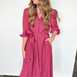 Woman wearing a pink dress against a white wall