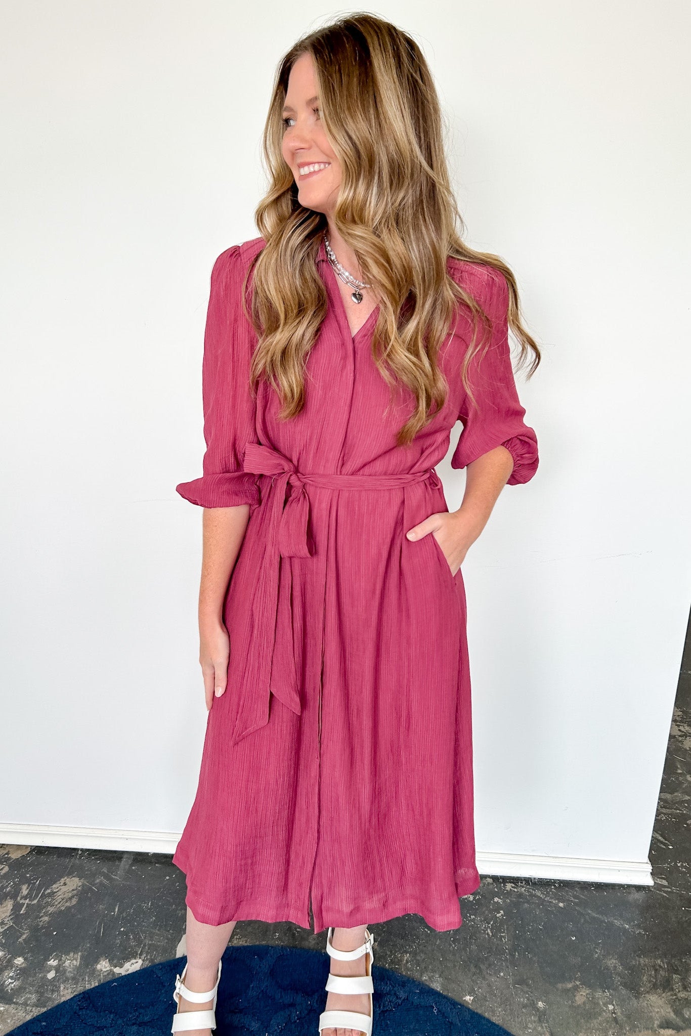 Woman wearing a pink dress against a white wall