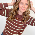 Woman wearing a brown and white striped sweater against a plain background