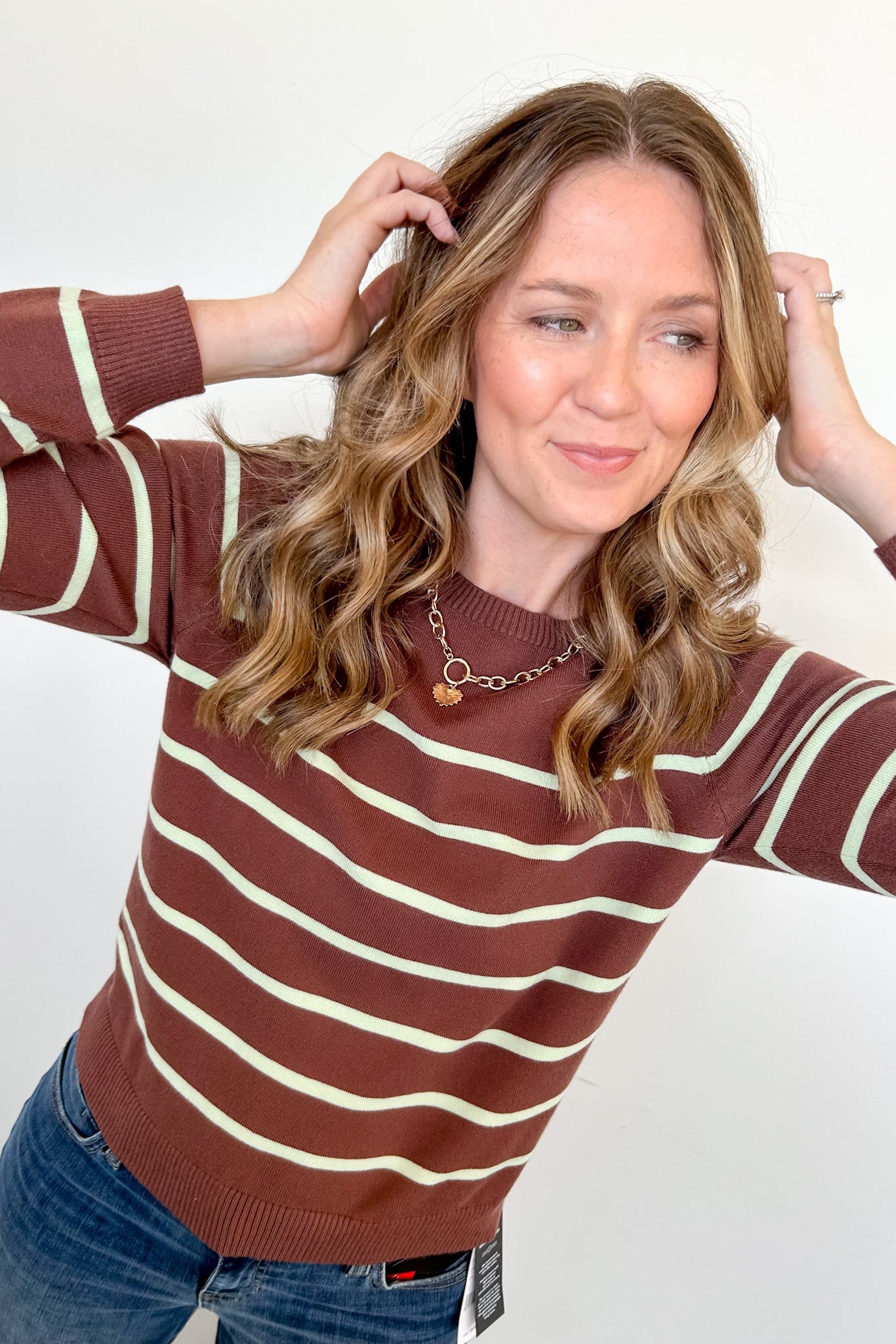 Woman wearing a brown and white striped sweater against a plain background