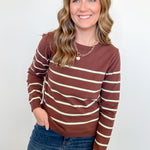 Woman wearing a brown and beige striped sweater and blue jeans against a white background