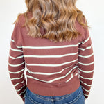 Person wearing a striped sweater and jeans on a white background