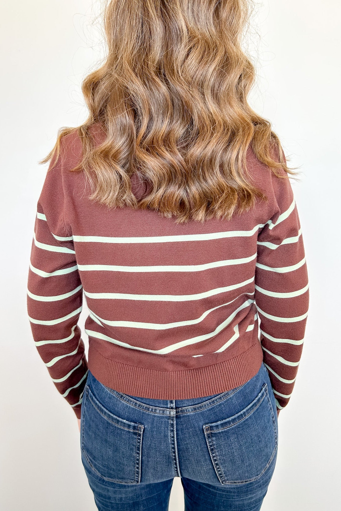 Person wearing a striped sweater and jeans on a white background