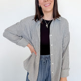 Woman wearing a striped shirt and blue jeans against a white wall