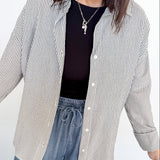 Woman wearing a striped shirt, black top, and blue jeans against a white background