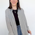 Woman wearing a striped shirt and blue jeans against a white wall