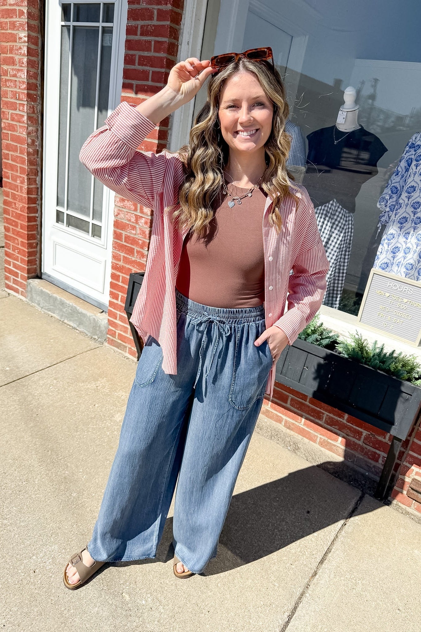 Woman in pink shirt and blue jeans standing outside a store