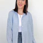 Woman wearing a blue and white striped shirt with a plain background