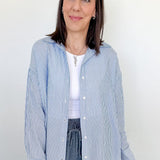 Woman wearing a blue and white striped shirt with a plain background