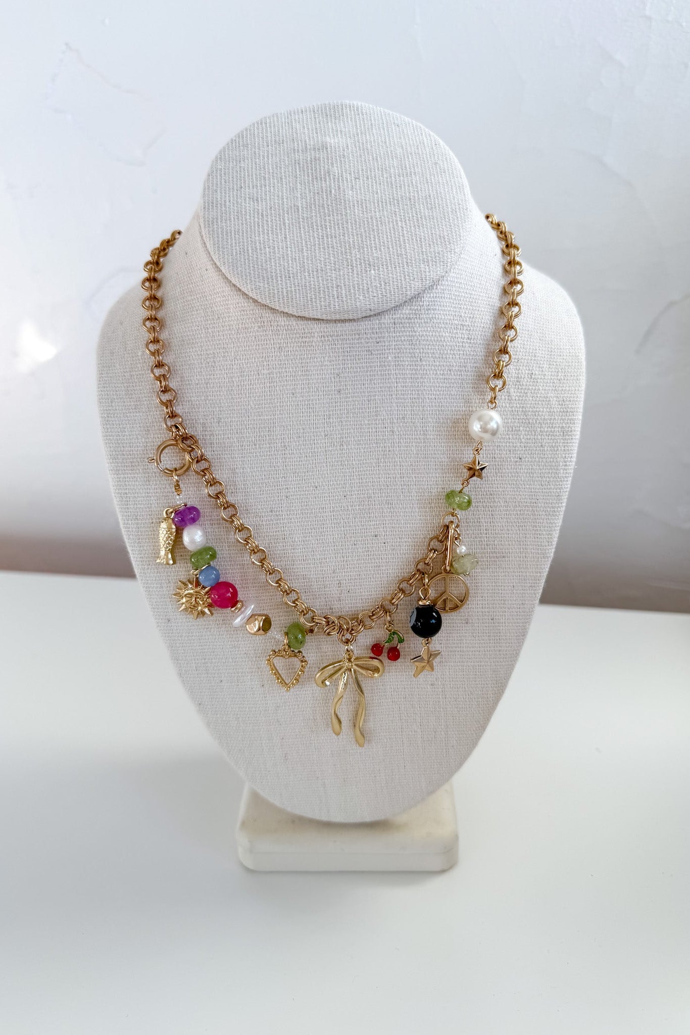 Necklace with colorful charms on a white bust