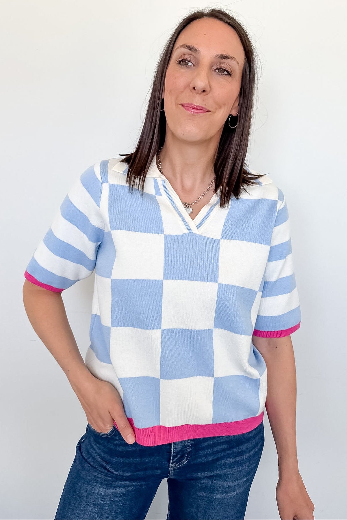 Woman wearing a checkered sweater with blue, white, and pink stripes against a plain background