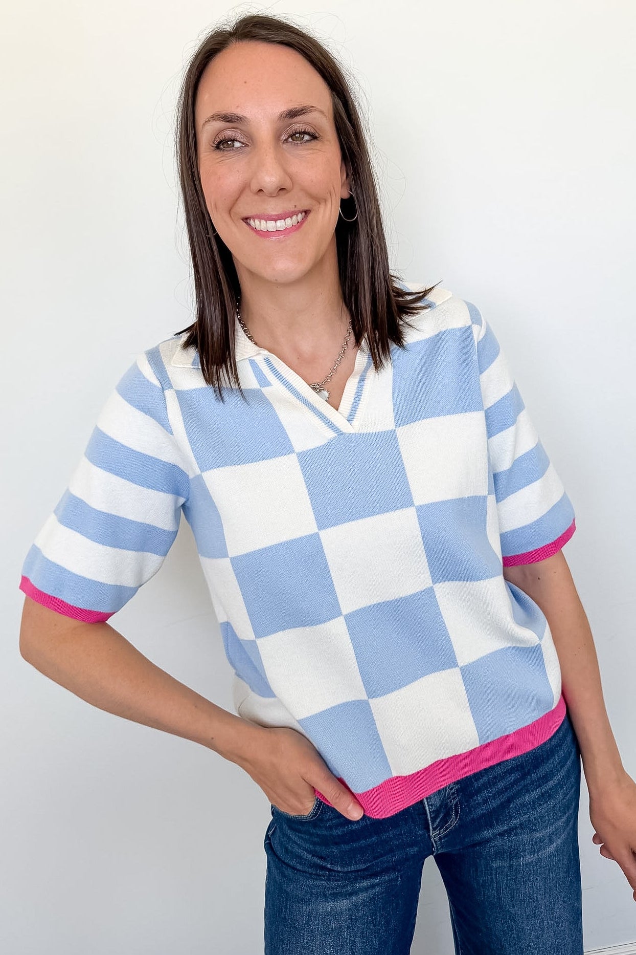 Woman wearing a checkered shirt with blue, white, and pink colors against a plain background
