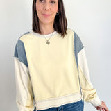 Woman wearing a cream and blue color-blocked sweatshirt against a white background