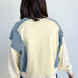 Person wearing a cream and blue patchwork sweater against a white background