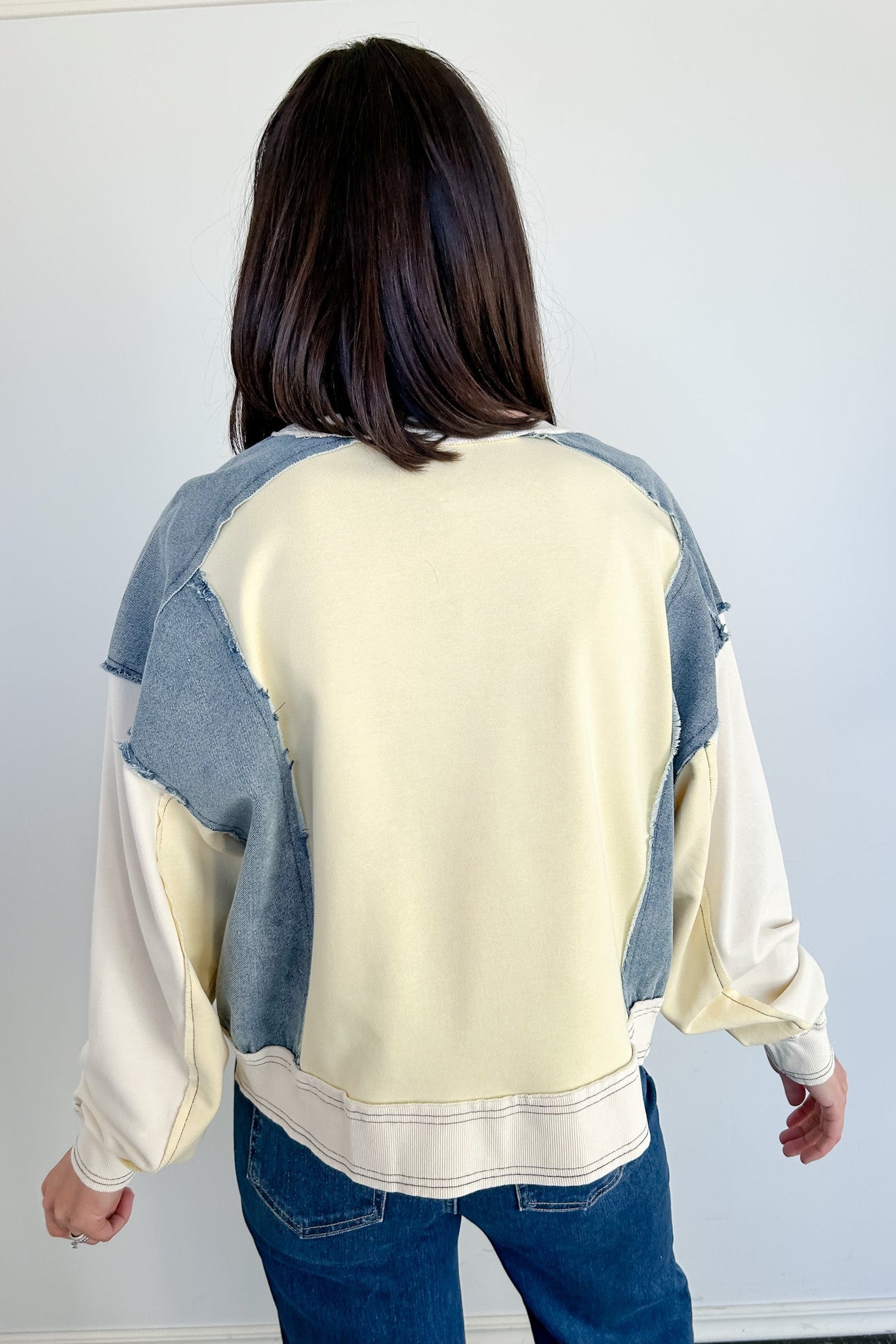 Person wearing a cream and blue patchwork sweater against a white background