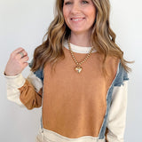 Woman wearing a brown and beige sweater with a denim collar against a white background