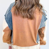 Person wearing a mustard yellow top and denim jacket with beige pants against a white background