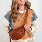 Woman holding a brown leather bag against a white background